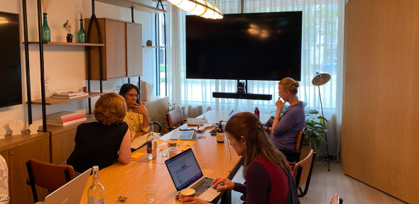 Researchers working on laptops and talking to each other at a retreat organised by our facilitation team